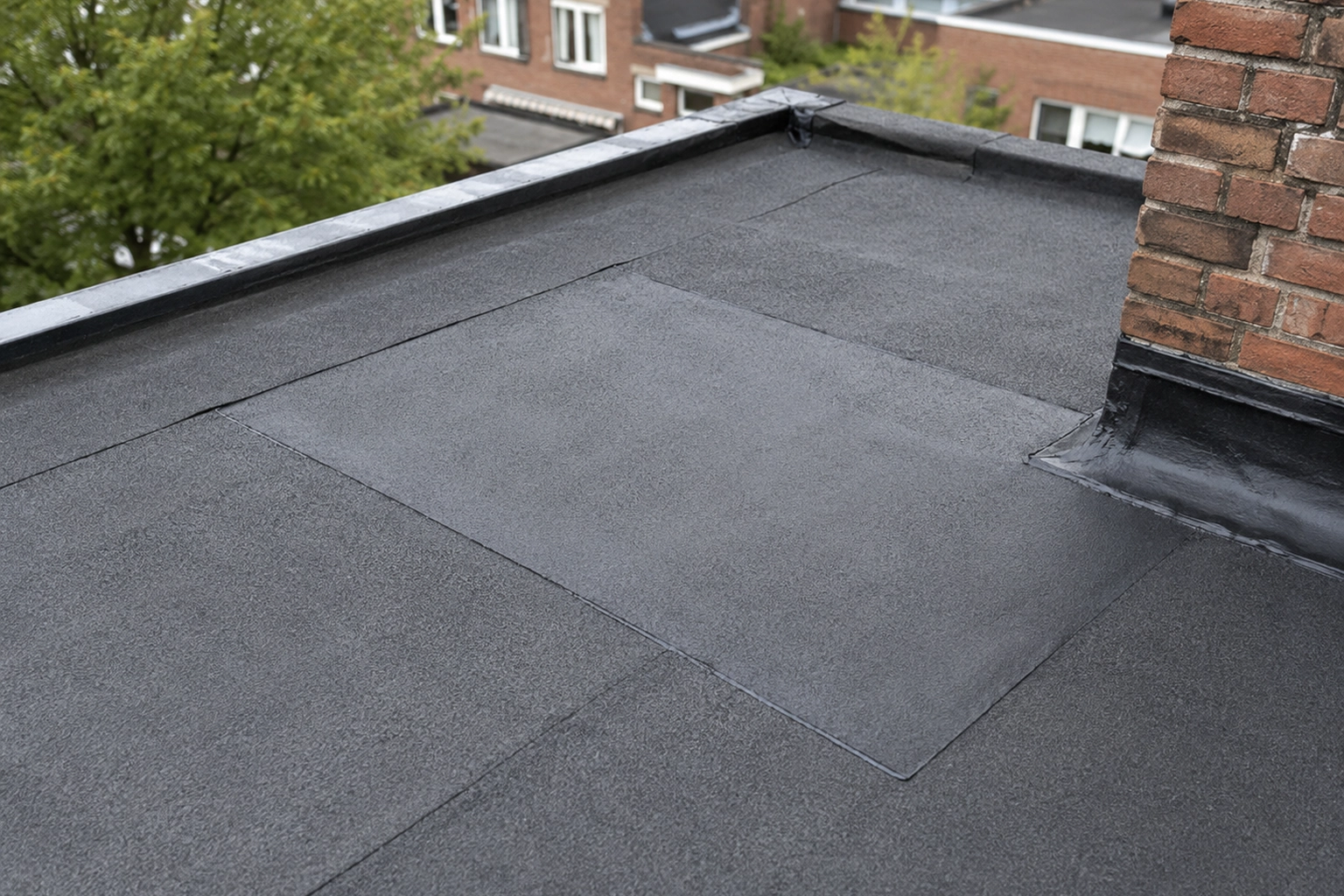 Plat dak met herstelde dakbedekking rond een gemetselde schoorsteen